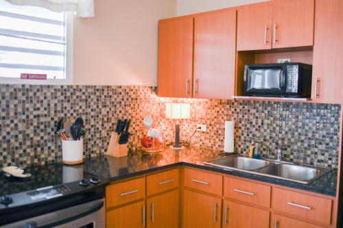 a kitchen with wooden cabinets and a sink and a microwave at Island Charm Culebra - Studios & Suites - Amazing Water views in Culebra Puerto Rico! in Culebra