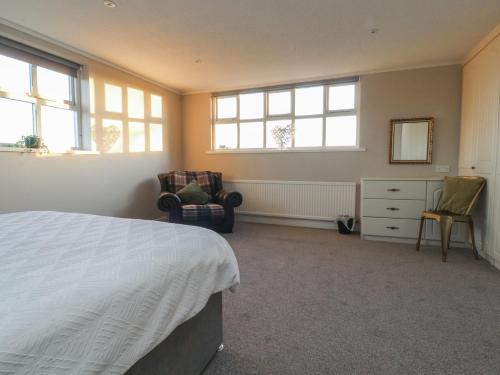 a bedroom with a bed and two chairs and windows at Homewood in Preston