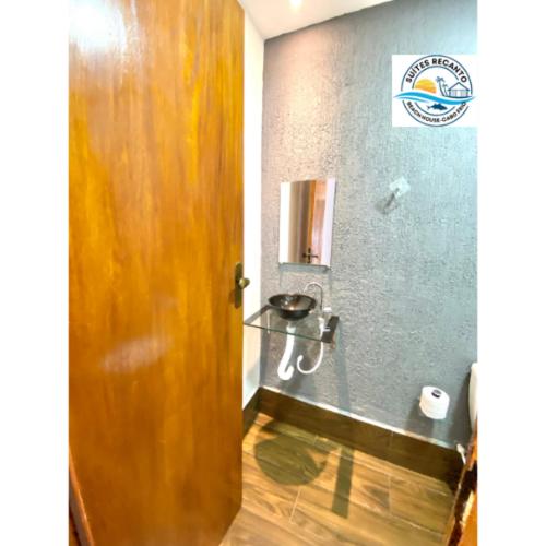 a bathroom with a wooden door and a sink at Pousada Recanto Beach House-CaboFrio-Unamar-condominio Florestinha in Cabo Frio