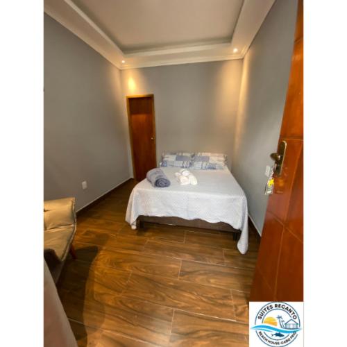 a bedroom with a bed with white sheets and blue pillows at Pousada Recanto Beach House-CaboFrio-Unamar-condominio Florestinha in Cabo Frio