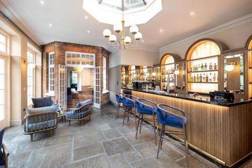a restaurant with a bar with blue chairs at Milford Hall Salisbury in Salisbury
