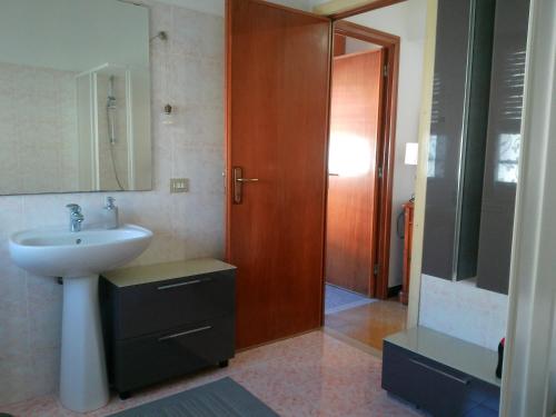 a bathroom with a sink and a wooden door at Cappuccini apartments superior in Oristano