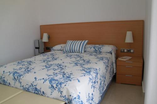 a bedroom with a blue and white bed and a wooden headboard at Ático Dos Bahías in Águilas