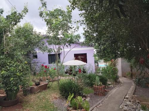 a white house with an umbrella in a garden at Pousada Oliveira in Ametista do Sul