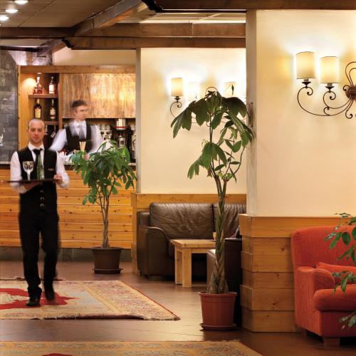 a man in a tuxedo standing in front of a bar at TH La Thuile - Planibel Hotel in La Thuile