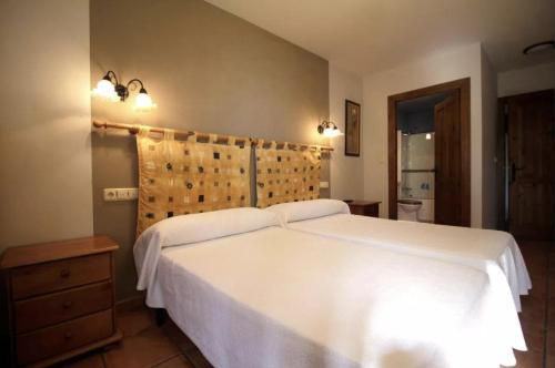 a bedroom with a large white bed and two lights at Hotel Rural Alavera in San Martin del Mar