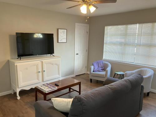 a living room with a couch and a flat screen tv at The Purple House - Cozy Near TSU in Stephenville