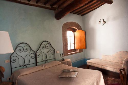 a bedroom with a bed and a chair and a window at La Locanda del Loggiato in Bagno Vignoni