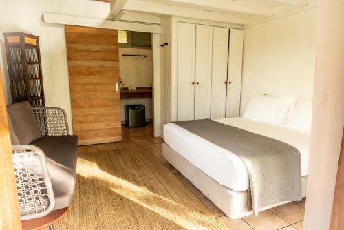 a bedroom with a white bed and a chair at Moorea Island Beach Hotel in Moorea