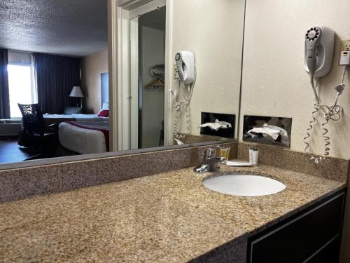 a bathroom counter with a sink and a mirror at Budget Inn Laramie in Laramie