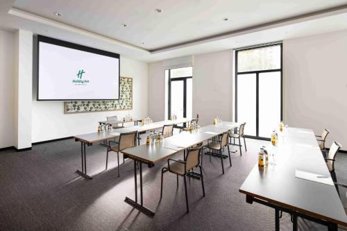 a room with tables and chairs and a projection screen at Holiday Inn Frankfurt - Alte Oper by IHG in Frankfurt/Main