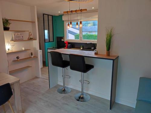 une cuisine avec un bar avec des tabourets et un évier dans l'établissement Ty Moon, à Lannion