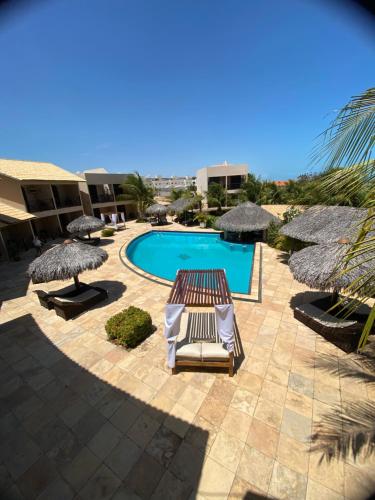 a swimming pool with two lounge chairs and umbrellas at Pousada Aruana in Canoa Quebrada