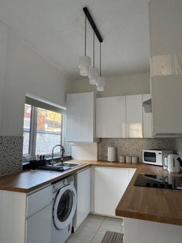 a kitchen with white cabinets and a washing machine at Gertrude house in Saint Helens