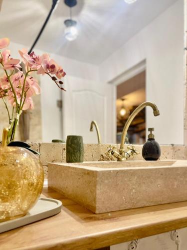 a bathroom counter with a sink and a vase of flowers at Saints & Sinners Romantic Jacuzzi in Bucharest