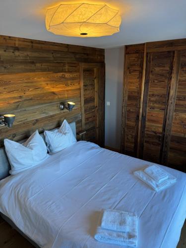 a bedroom with a large white bed with wooden walls at Clair Vue A2 Telecabine by Jolidi in Nendaz