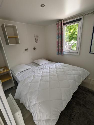 - un lit blanc dans une chambre avec fenêtre dans l'établissement Mobil-home l'albanou, au Pouzin