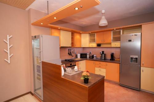 cocina grande con armarios naranjas y electrodomésticos de acero inoxidable en Guest house Traikovi, en Petrich