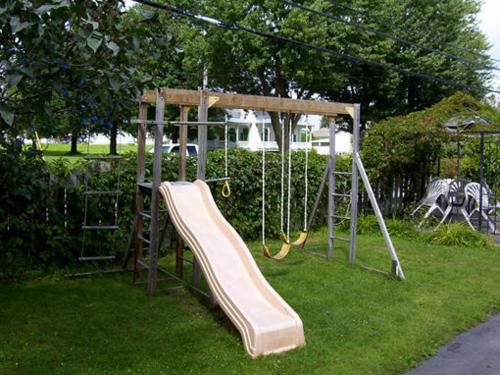 a playground with a slide in the grass at Motel Montgolfière JP in Saint-Jean-sur-Richelieu