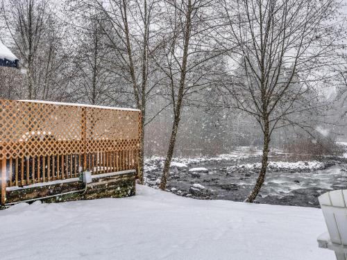 a fence covered in snow next to a river at Riverbend Cabin 1 - Lolo Bungalow in Rhododendron