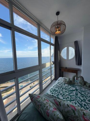 ein Schlafzimmer mit einem Bett und einem großen Fenster mit Blick auf das Meer in der Unterkunft Sunrise in Calpe