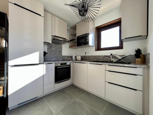 une cuisine avec des armoires blanches et une fenêtre dans l'établissement Homency - Résidence L'Expression A11, à L'Alpe-d'Huez