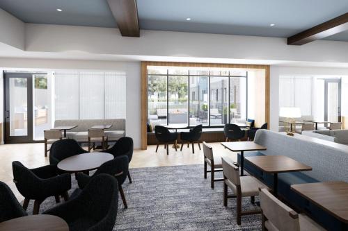 a waiting room with tables and chairs and windows at Staybridge Suites Southaven - Memphis South by IHG in Southaven