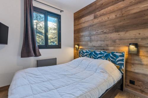 - une chambre avec un lit et un mur en bois dans l'établissement Résidence Le Balcon Des Airelles - Appartement calme au cœur des Orres 1800 MAE-9434, aux Orres