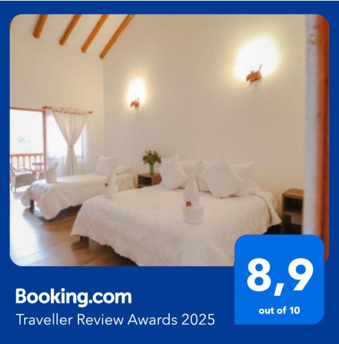 a white bedroom with two beds and a window at Hotel las Palmas in Villa de Leyva
