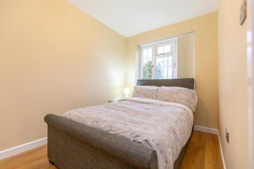 ein Bett in einem Zimmer mit Fenster in der Unterkunft Wootton 2-Bedroom Bungalow in Hardingstone