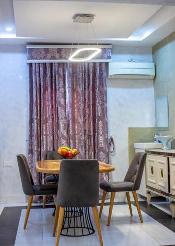 a dining room with a table and chairs and a curtain at Ugo Homes in Abuja
