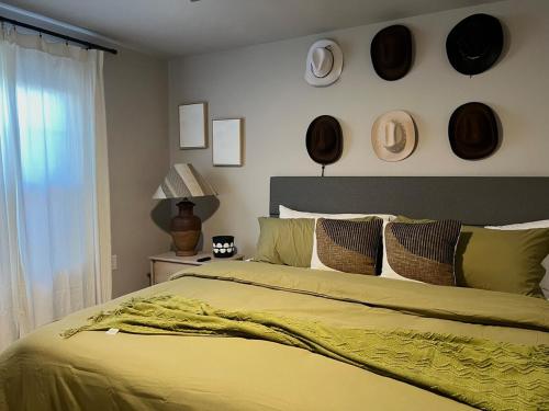 a bedroom with a yellow bed with hats on the wall at The Cottage Tavern- w Smoothie's Bar NR Tech in Lubbock