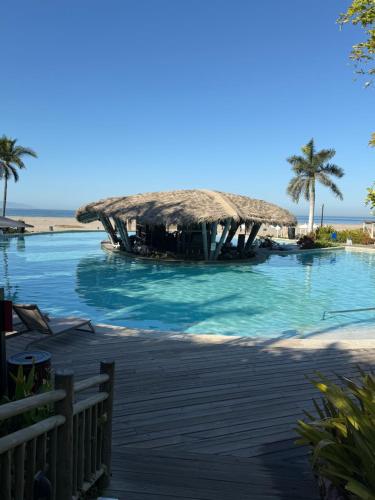 a resort swimming pool with a thatched roof on the beach at Luxurious 2 Bedroom Upscale Condo in Nuevo Vallarta 