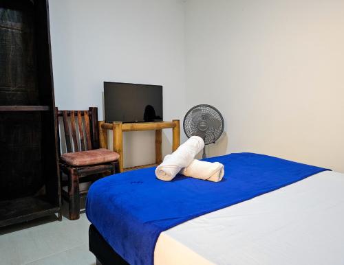 a room with a bed with a fan and a chair at Maisant Hostel in Cali