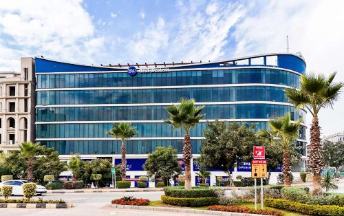 a large glass building with palm trees in front of it at Best Western Hotel Rawalpindi Central in Rawalpindi