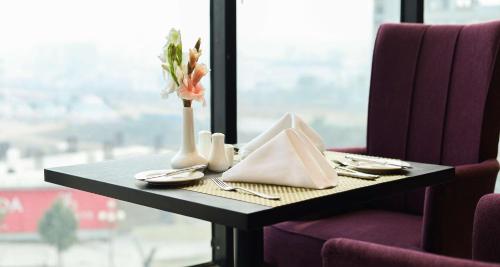 a table with plates and a vase with flowers on it at Best Western Hotel Rawalpindi Central in Rawalpindi