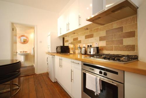 a kitchen with white cabinets and a stove top oven at London Collection - Old Compton Soho in London