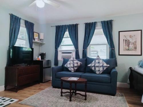 a living room with a blue couch and two windows at Cherokee Lodge in San Diego