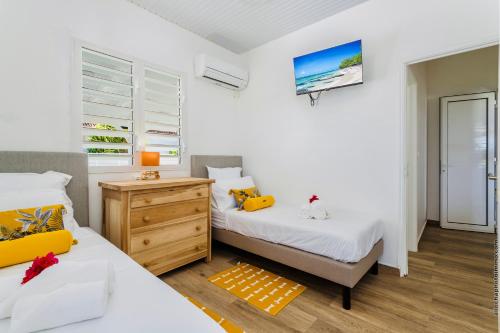 a bedroom with two beds and a wooden dresser at Villa Tropic Hirondelle - Piscine Vue Mer in Le François