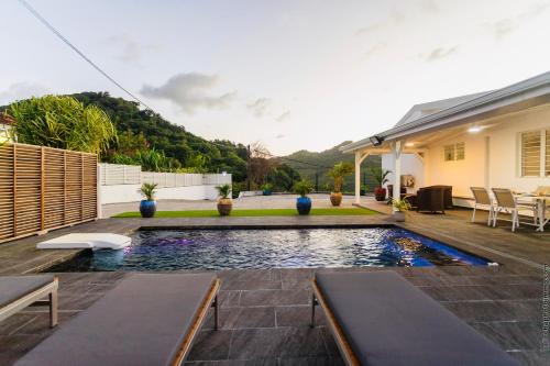 a backyard with a swimming pool and a house at Villa Tropic Hirondelle - Piscine Vue Mer in Le François