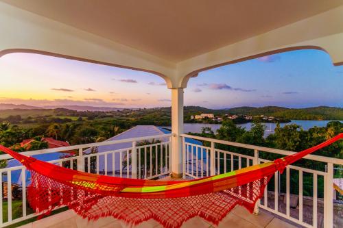 a hammock on a balcony with a view of the water at Villa Tropic Hirondelle - Piscine Vue Mer in Le François