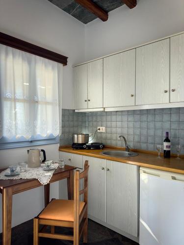a kitchen with white cabinets and a table and a sink at Anatoli in Ano Meria