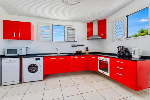 a kitchen with red cabinets and a washer and dryer at Villa Tropic Hirondelle - Piscine Vue Mer in Le François