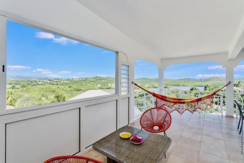 a balcony with a hammock and a table and chairs at Villa Tropic Hirondelle - Piscine Vue Mer in Le François