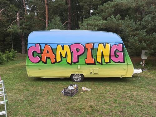 a caravan with the word camping painted on the side of it at SP camping Spāres Prieduļi in Nīca