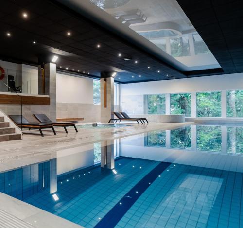 a swimming pool with blue tiles in a building at Hotel Shuum Boutique - Destigo Hotels in Kołobrzeg