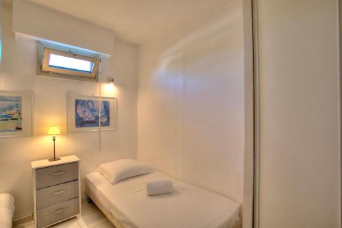 une petite chambre avec un lit et une fenêtre dans l'établissement GOLFE JUAN, Cosy T3 , piscine , parking, au Golfe-Juan