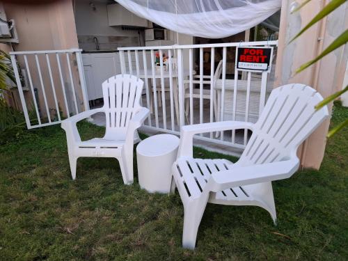 three white chairs sitting next to a white fence at Just in paradise in Baie Nettle
