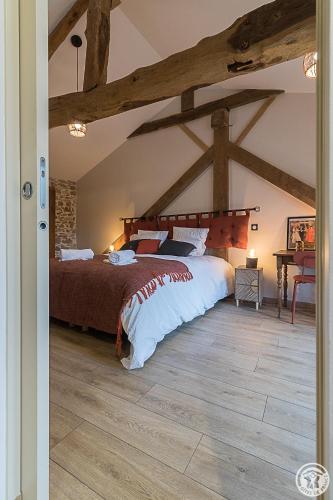 a bedroom with a large bed with wooden beams at La Ferme des Hautins - Chambres -d'Hôtes in Rieucazé