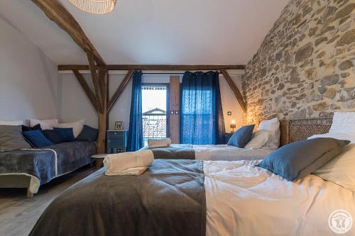 a living room with two beds and a stone wall at La Ferme des Hautins - Chambres -d'Hôtes in Rieucazé